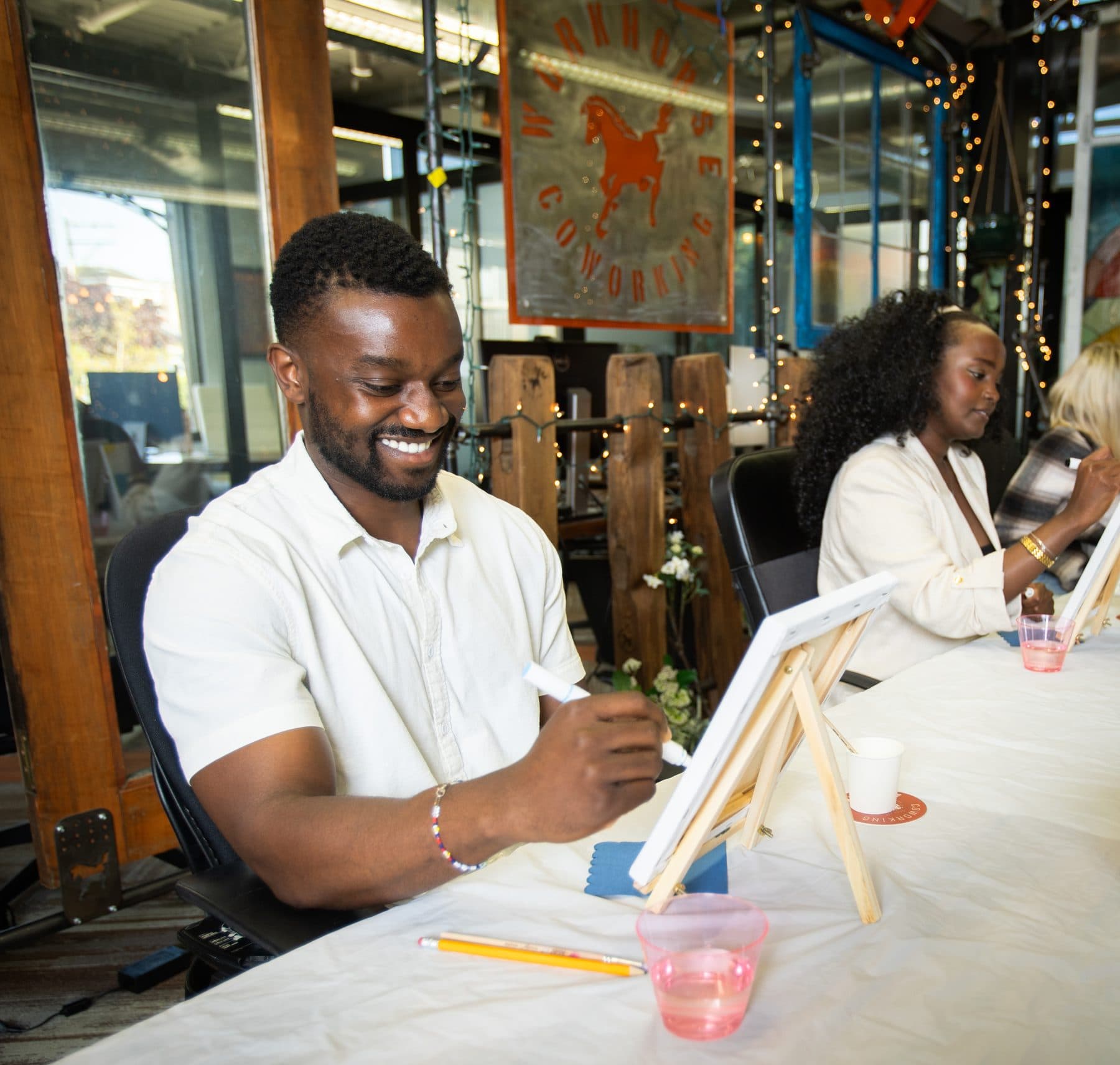 A member painting at a tabletop easel during a sip-and-paint evening.