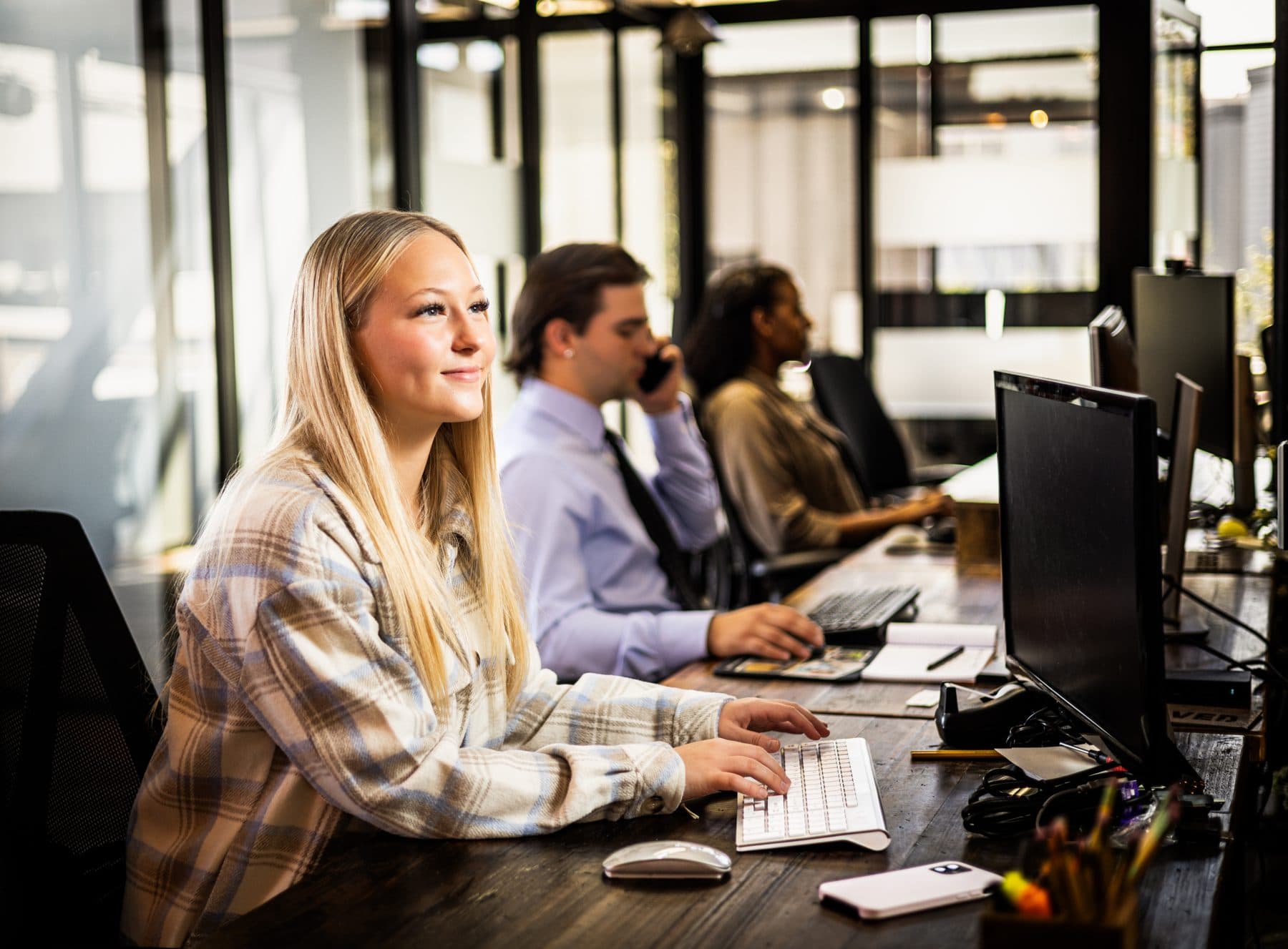 A member at her keyboard in a row of dedicated desks, colleagues working further down the row.
