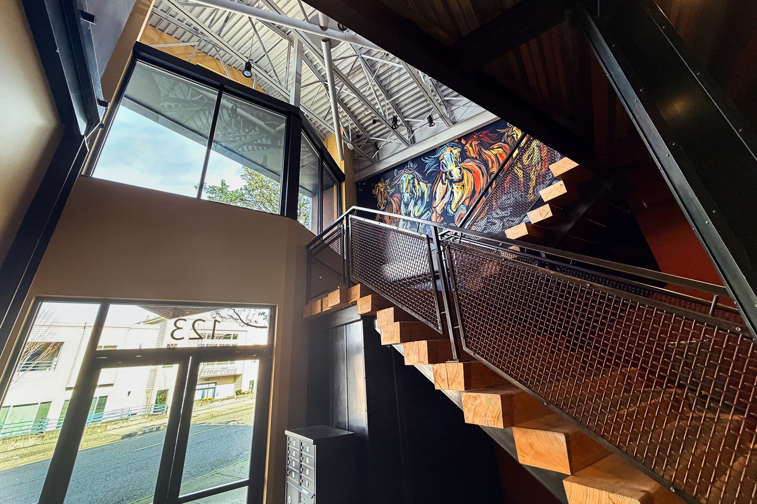 The entry stairwell looking up toward the painted horse mural, with the building number on the glass door.