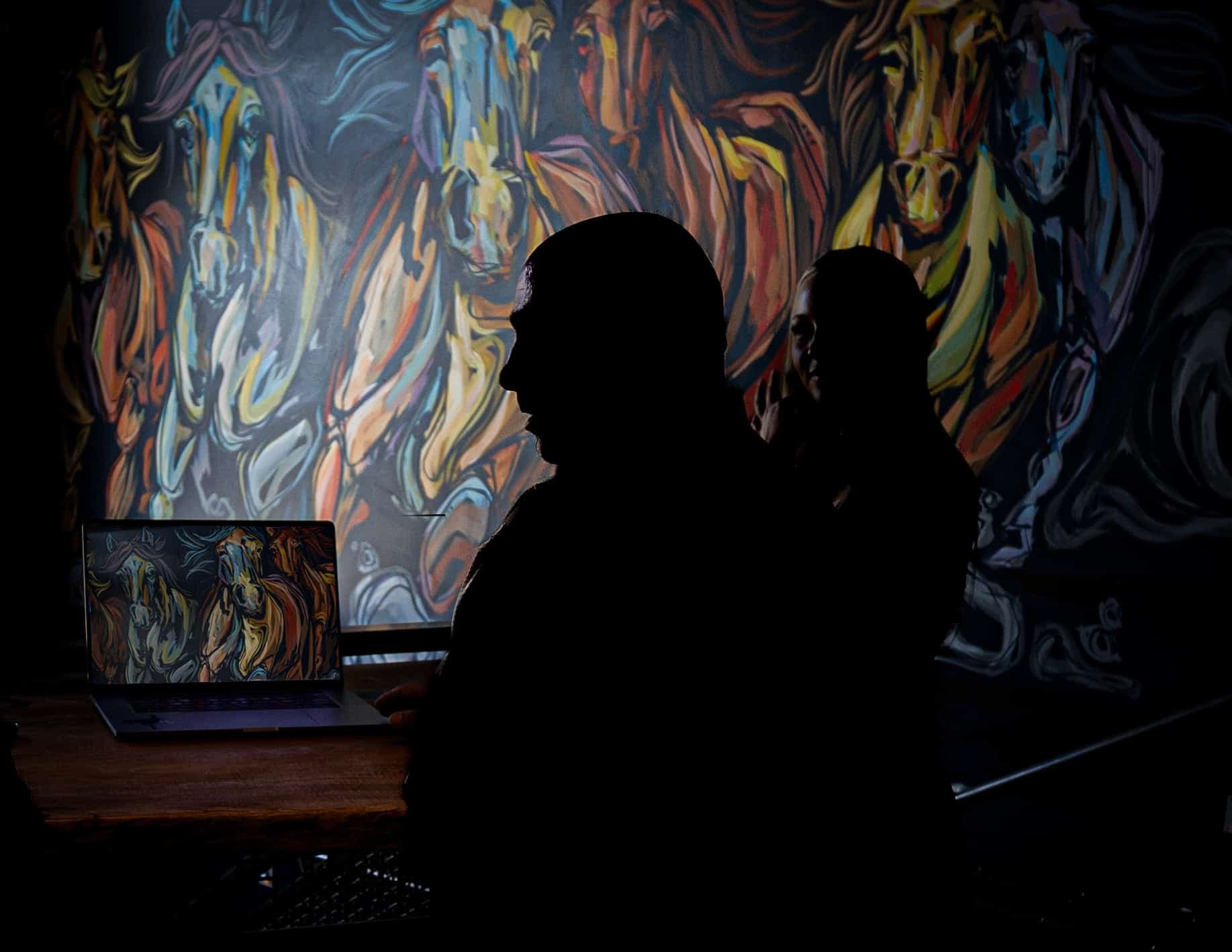 A silhouette of someone admiring a moody mural.