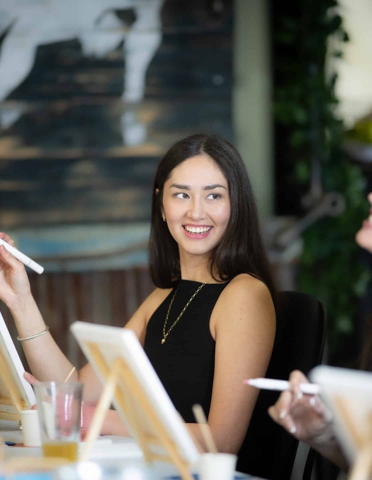 A guest laughing at a paint night, blank canvases on easels in front of her