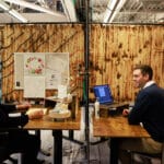 Two desk mates chatting with each other as they work.