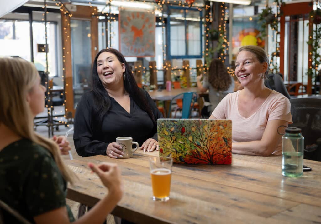 Three Ladies sitting at a Workhorse Coworking space laughing and chatting