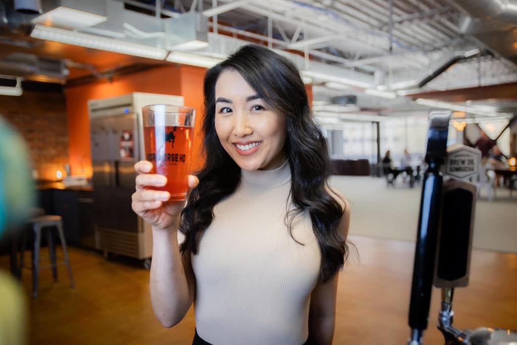 Woman holding a glass of kombucha at Workhorse Coworking in Edmonds