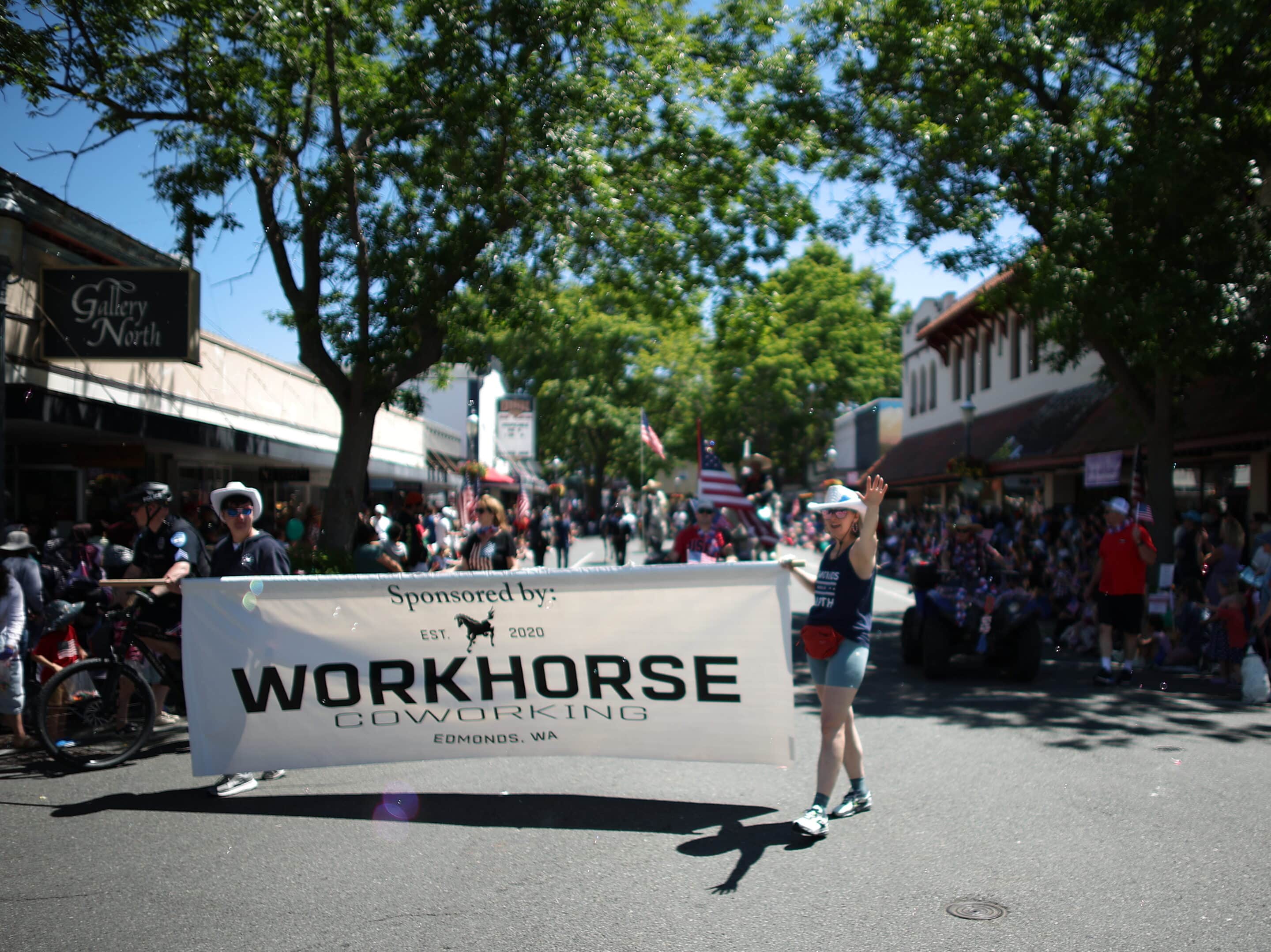 Workhorse Banner with two people holding it walking down a main street in a Parade. 