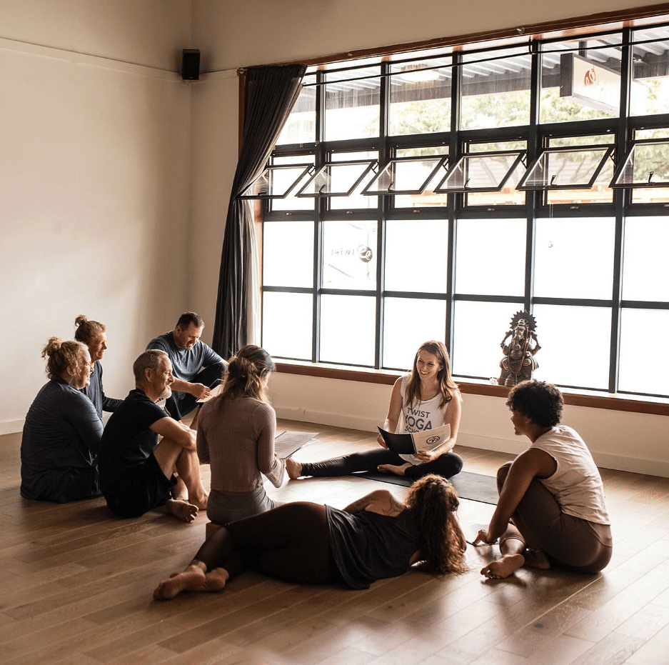 Smiling people sitting in a circle during class at Twist Yoga